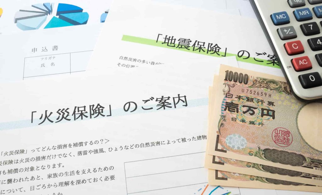 火災保険や地震保険の申込書と電卓とお金